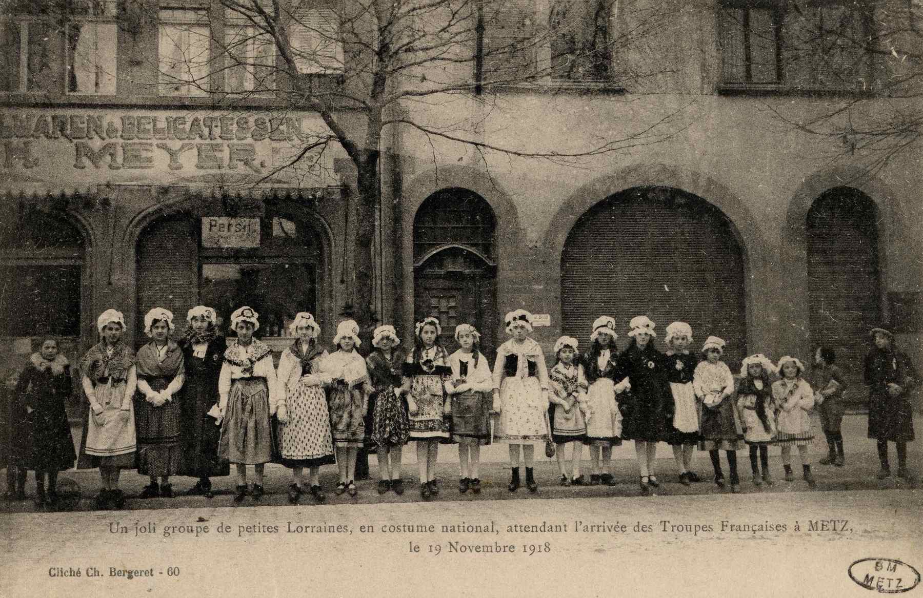 Contenu du Un joli groupe de petites Lorraines, en costume national, attendant l'arrivée des Troupes Françaises à Metz le 19 novembre 1918